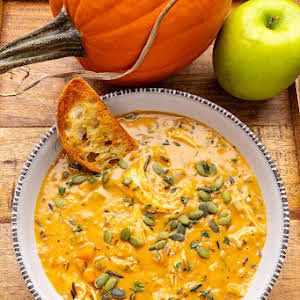 a white bowl filled with soup next to an orange pumpkin