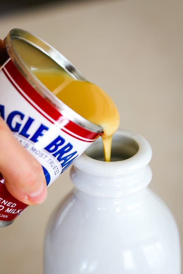 a person pouring orange juice into a white bottle