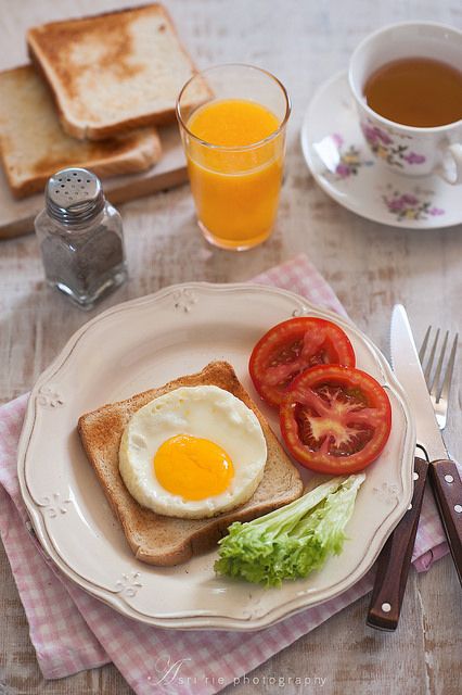 an egg, tomato and lettuce sandwich on a plate next to a cup of tea