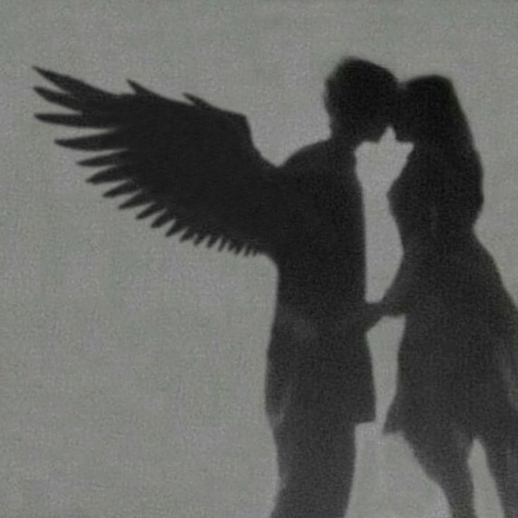 the shadow of two people kissing in front of an angel