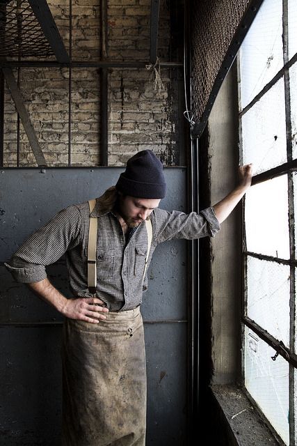 a man in an apron leaning against a window