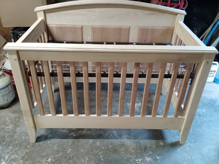 a wooden crib sitting on top of a floor next to a pile of tools