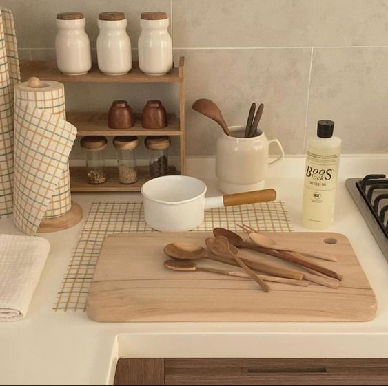 wooden utensils are sitting on a cutting board next to other kitchen accessories and jars