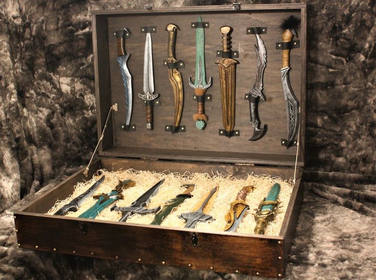 an old wooden box filled with lots of different types of swords and knives on display