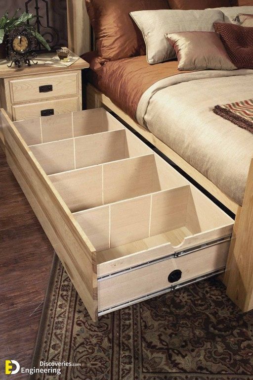 a bed with drawers underneath it on top of a carpeted floor next to a night stand