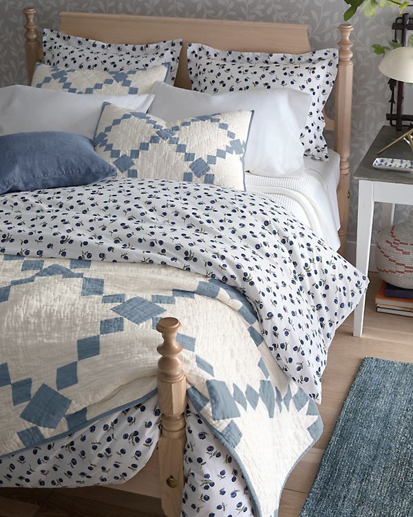 a bed with blue and white quilts in a bedroom next to a night stand