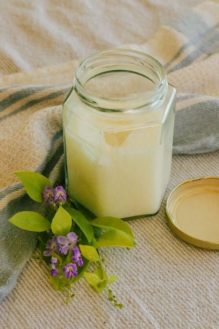 a glass jar sitting on top of a bed next to a flower