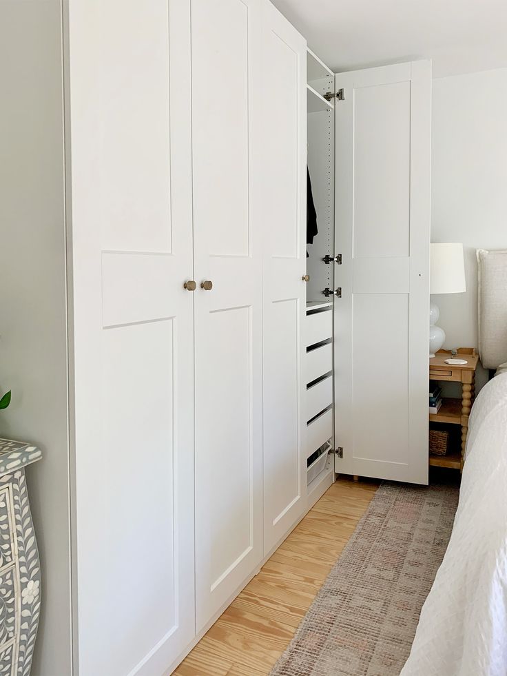 a bedroom with white closets and wood flooring next to a bed in the corner