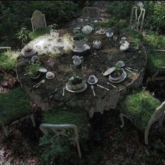 an old table is set with dishes and plates in the middle of a wooded area