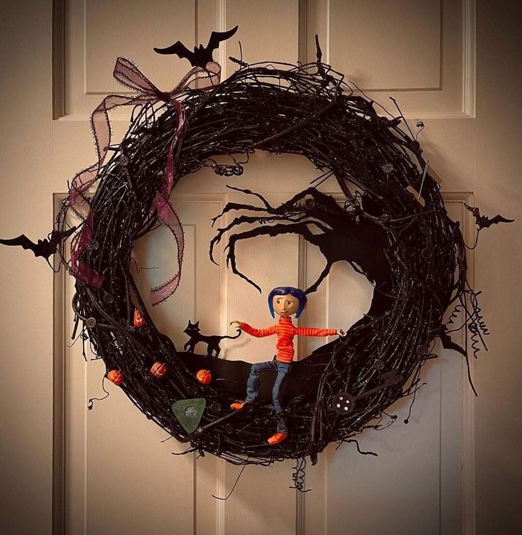 a halloween wreath is hanging on the front door with a doll in it's hand