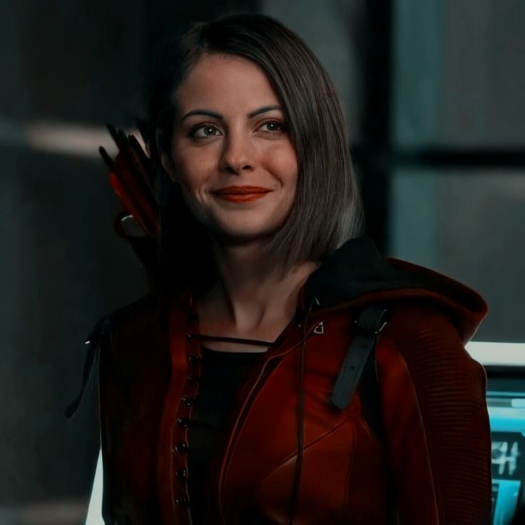 a woman in a red leather jacket and orange lipstick is looking at the camera with an evil look on her face