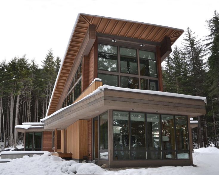 a modern house in the snow surrounded by trees