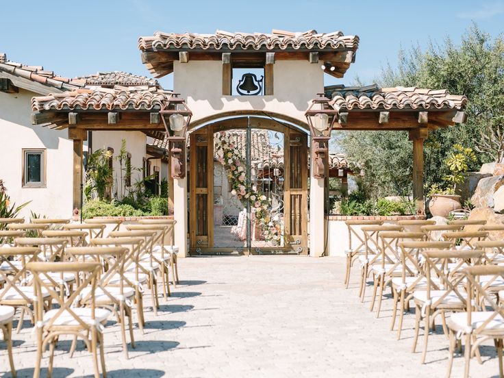 an outdoor wedding venue set up with wooden chairs