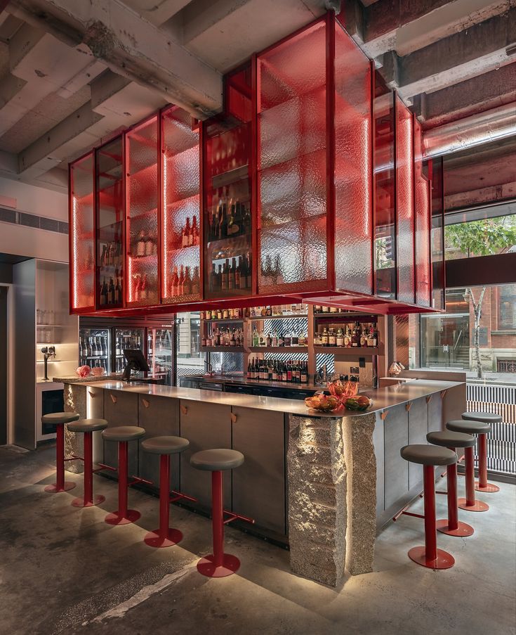 a bar with stools and shelves filled with bottles on the wall next to it