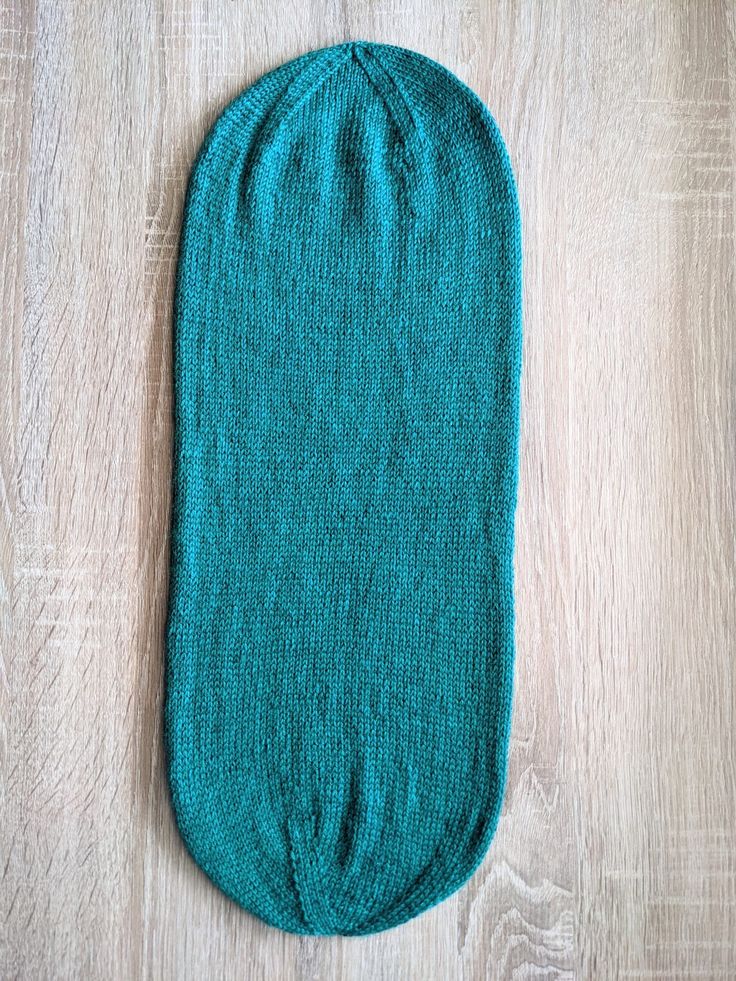 a teal colored sock laying on top of a wooden floor