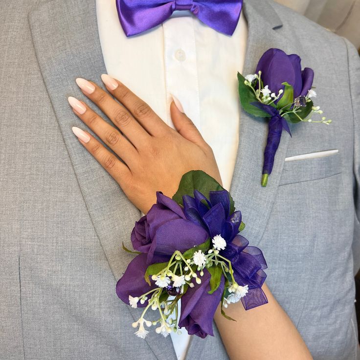 a man in a gray suit with purple flowers on his lapel and boutonniere