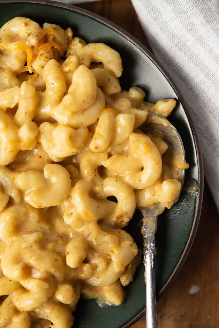 macaroni and cheese is served on a plate with a silver serving utensil