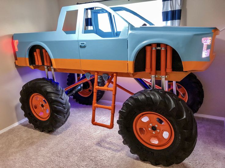 an orange and blue monster truck is on display in a children's playroom