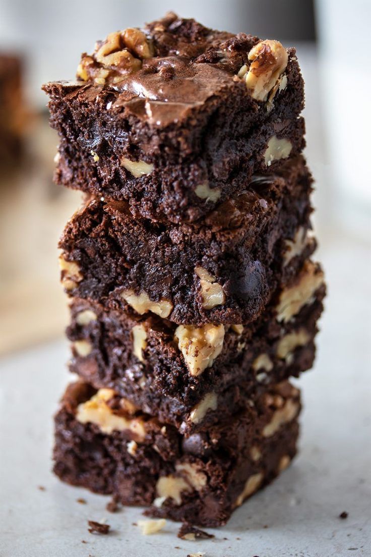 three brownies stacked on top of each other with chocolate frosting and walnuts