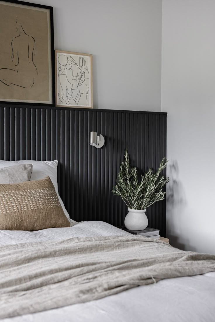 a bed with white sheets and pillows next to a painting on the wall above it