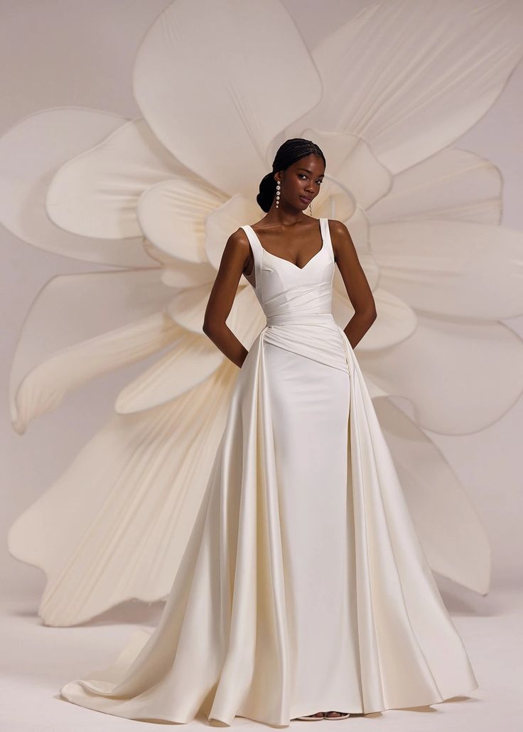 a woman in a white dress standing next to a large flower