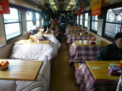 people are sitting at tables in the dining car of a train that is parked next to each other