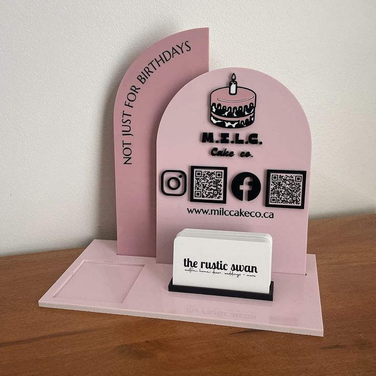 there is a pink cake stand with a business card holder in front of it on the table