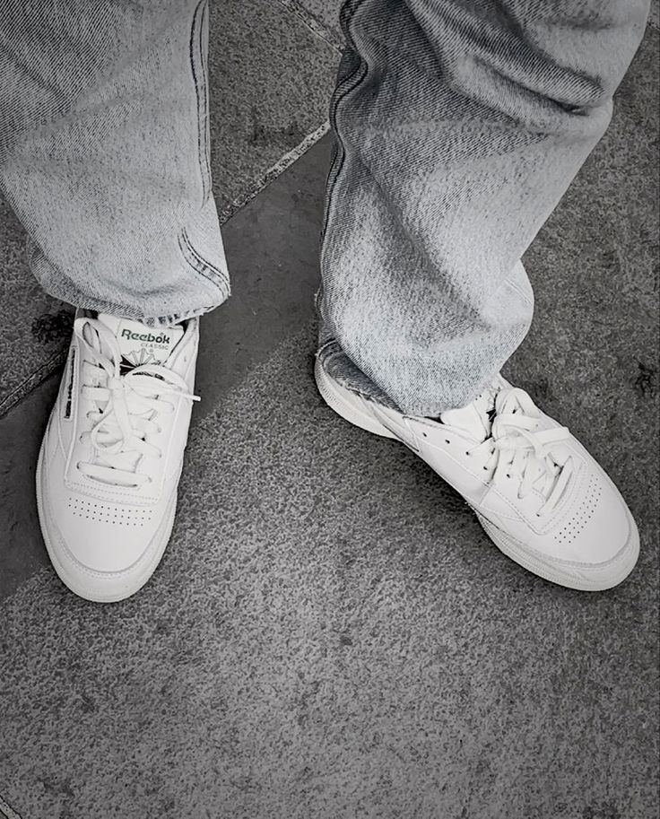 a person wearing white tennis shoes and jeans