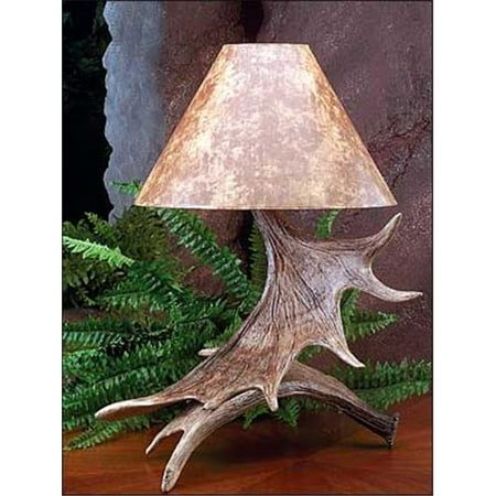 a lamp that is sitting on top of a wooden table next to some plants and rocks