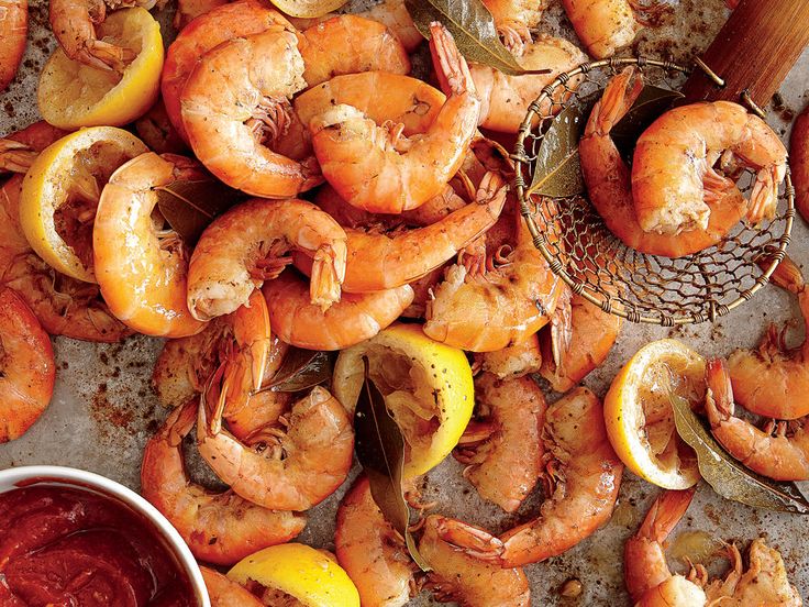 cooked shrimp and lemons on a baking sheet with ketchup