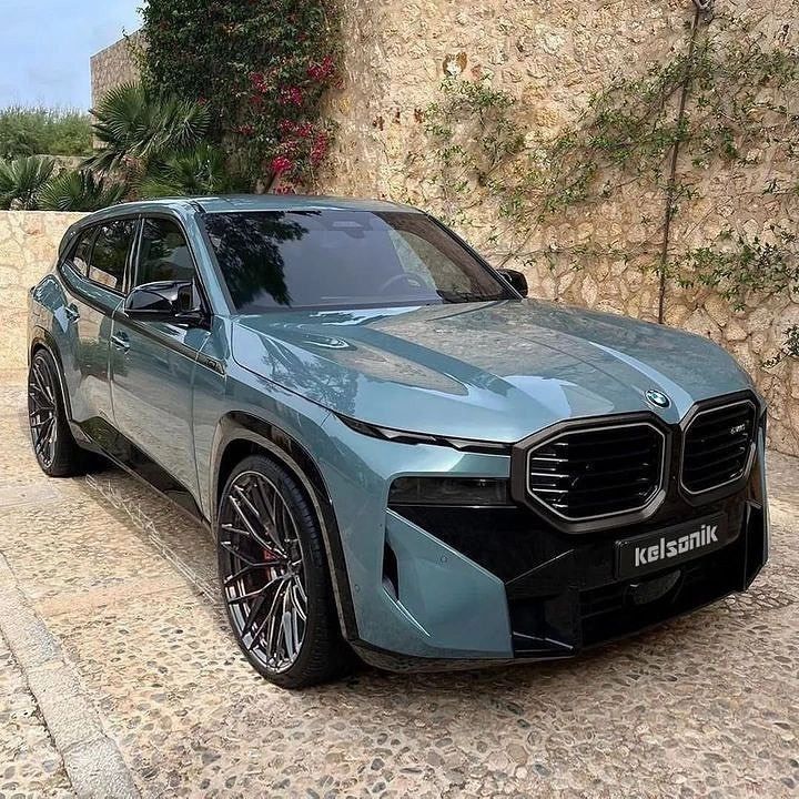 a blue bmw suv parked in front of a stone wall