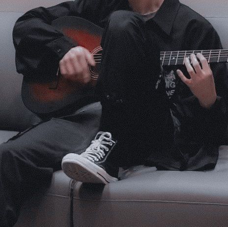 a man sitting on top of a couch holding a guitar