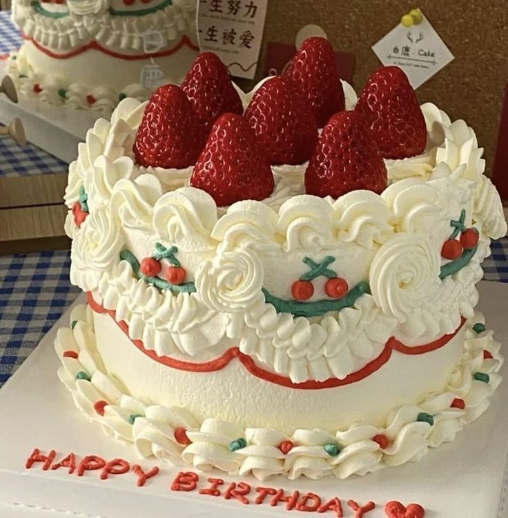 a white cake with strawberries on top and happy birthday written on the side in chinese