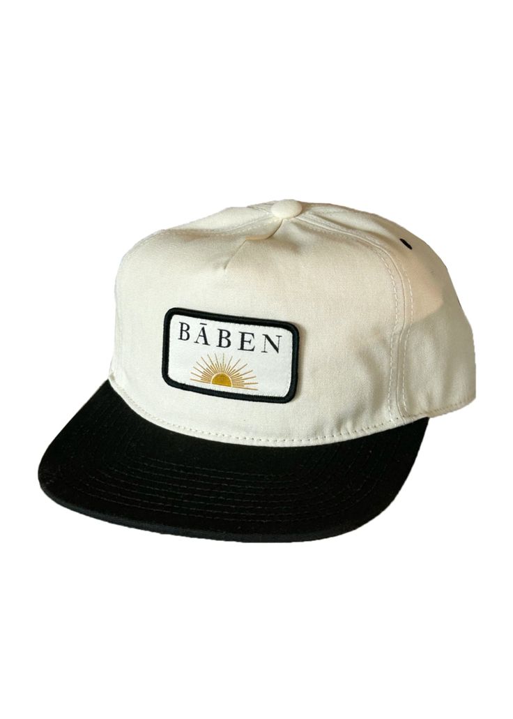 The BĀBEN cap is easy to wear for days spent in the sun. The hat is a mid-profile unstructured 5 panel cap cut in cotton canvas. It features an adjustable fit with a metal slider closure and a woven patch logo. Keeping it neutral with a two-tone creme and black colorway, it is versatile and perfect for salty hair days. Vintage pin not included. Fabric & Care Instructions: 100% Cotton Canvas Adjustable Canvas Hat With Logo Patch, Urban Style Adjustable Baseball Cap For Summer, Trendy Cotton 5-panel Snapback Hat, Retro Adjustable Cotton Snapback Hat, Adjustable Retro Cotton Snapback Hat, Urban Adjustable Summer Baseball Cap, Urban Flat Brim Baseball Cap For Summer, Urban Style Flat Brim Snapback Hat For Summer, Urban Style Snapback Hat With Flat Brim For Summer