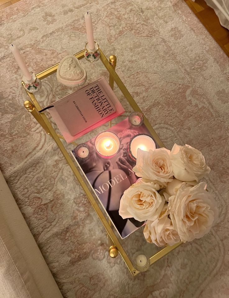 a tray with candles and flowers on top of a bed next to a book cover