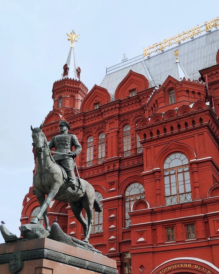 a statue of a man on a horse in front of a red building