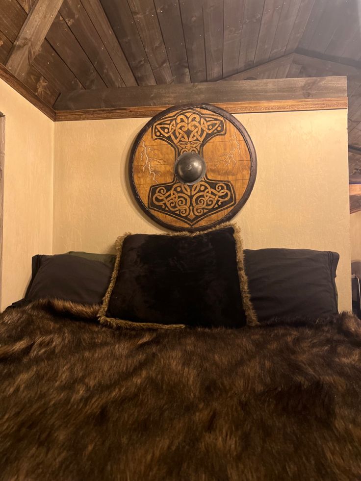 a bed with a brown and black comforter on top of it next to a wooden headboard