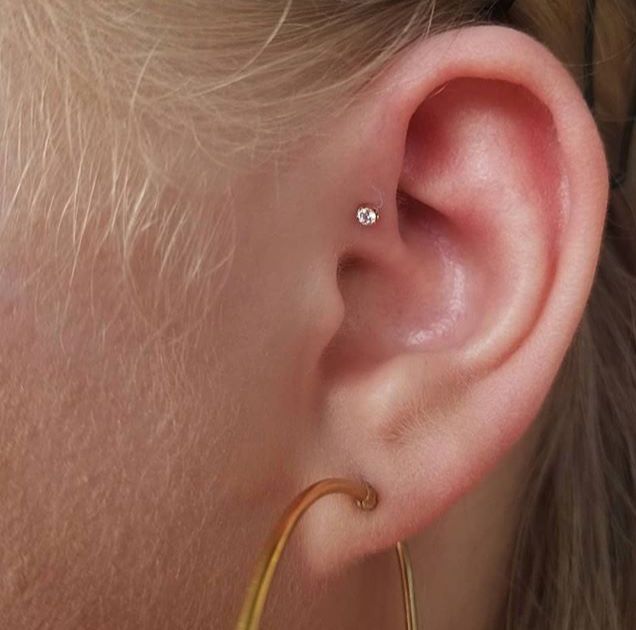 a close up of a person's ear with a gold hoop and diamond earrings