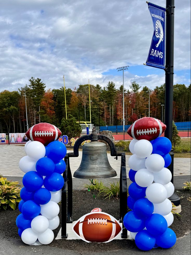 balloons and footballs are on display in front of a bell