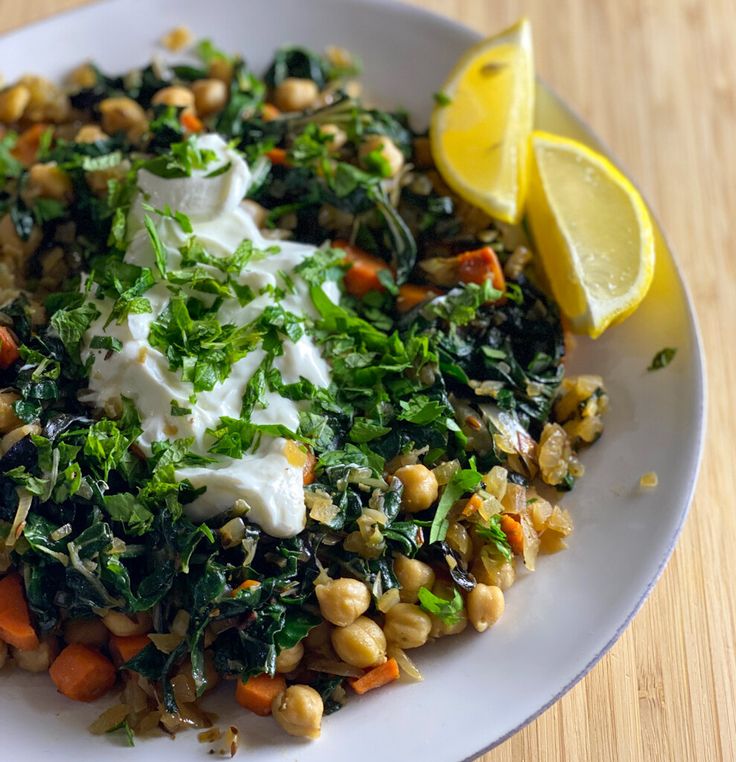 a white plate topped with lots of veggies next to a slice of lemon