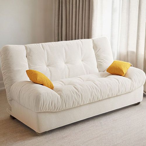 a white futon couch with yellow pillows on it in front of a curtained window