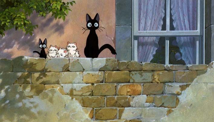 three black cats sitting on the ledge of a building