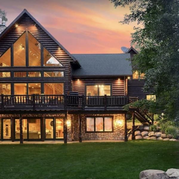 a large wooden house sitting on top of a lush green field next to a forest