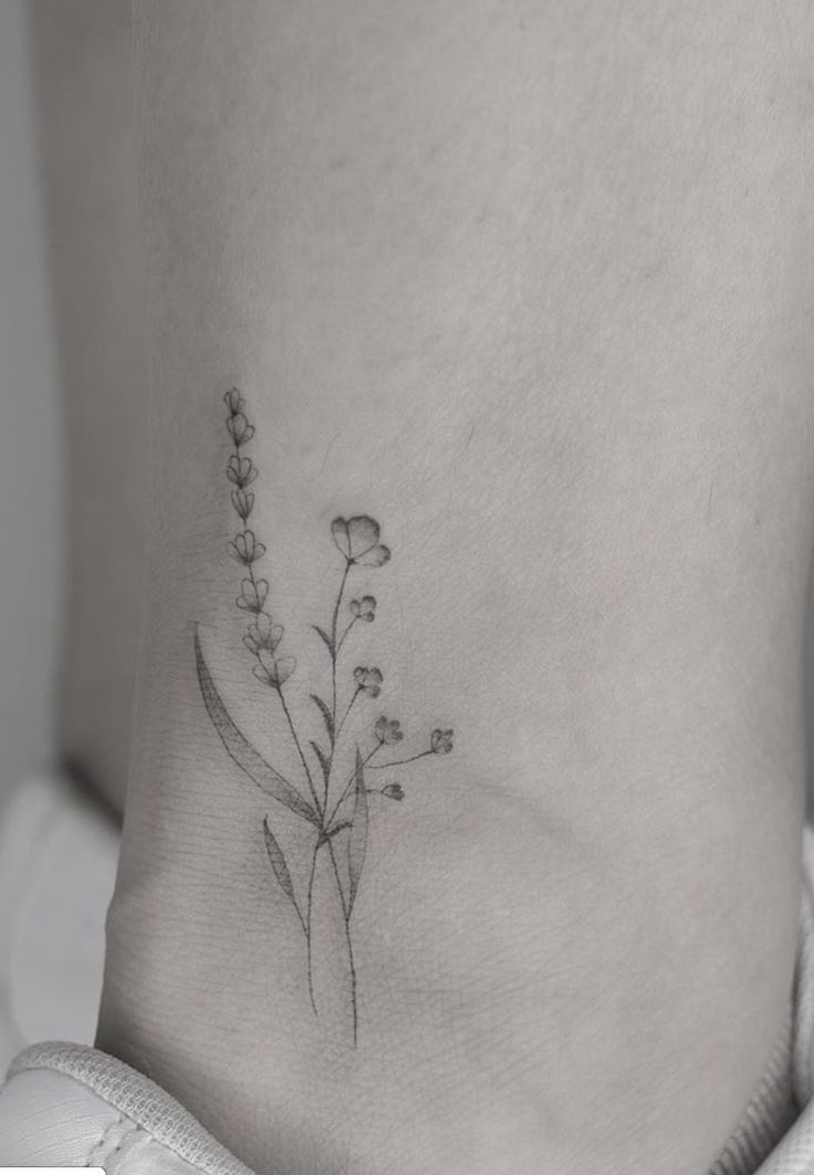 a small flower tattoo on the side of a woman's stomach is shown in black and white