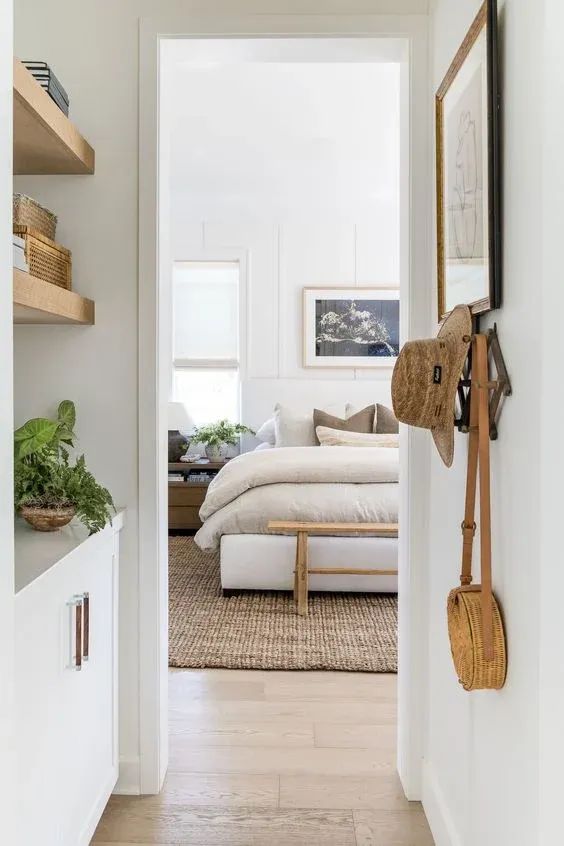 an open door leading to a bedroom with white walls and wooden shelves on either side