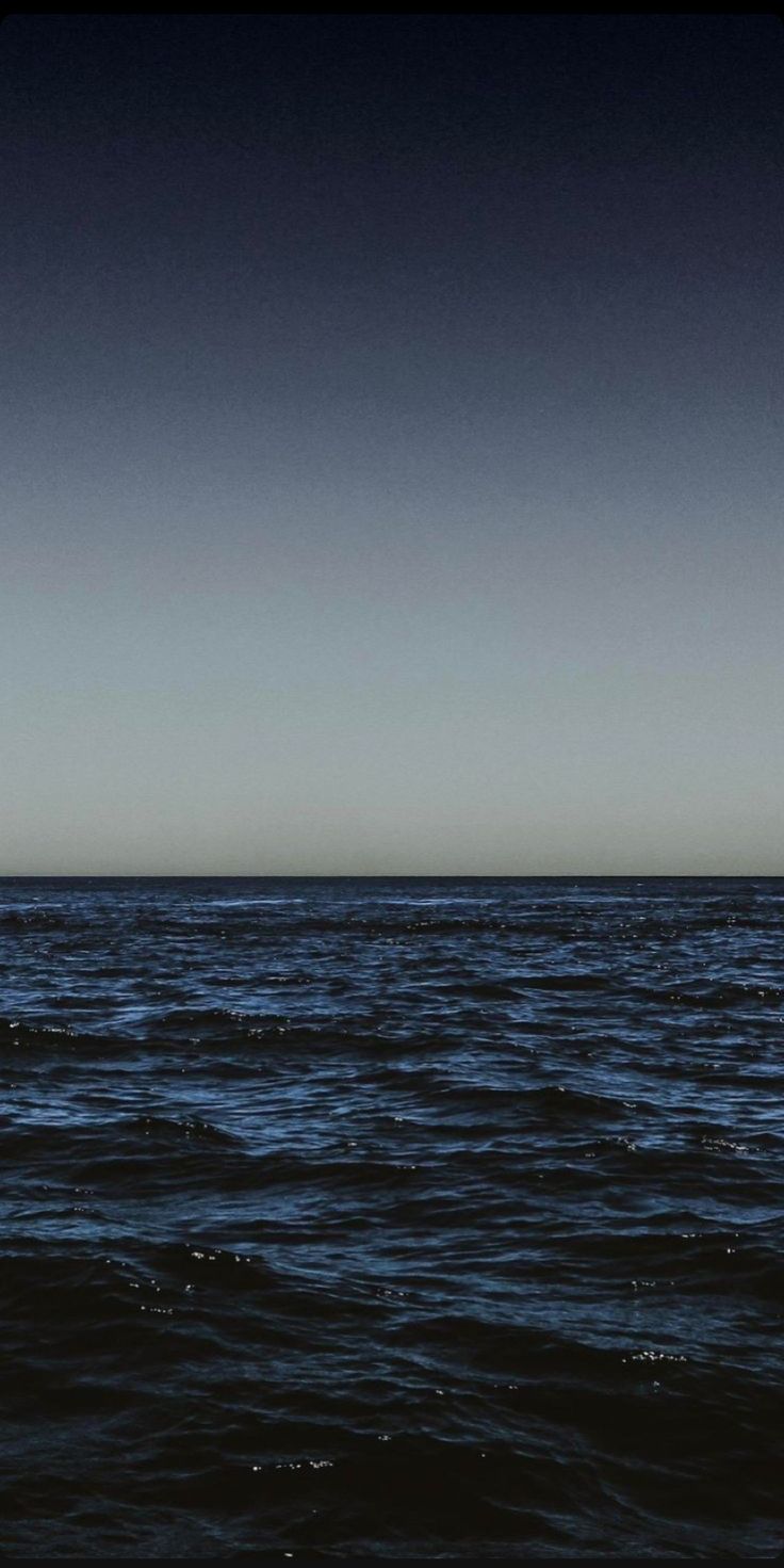 a lone boat floating in the ocean at night