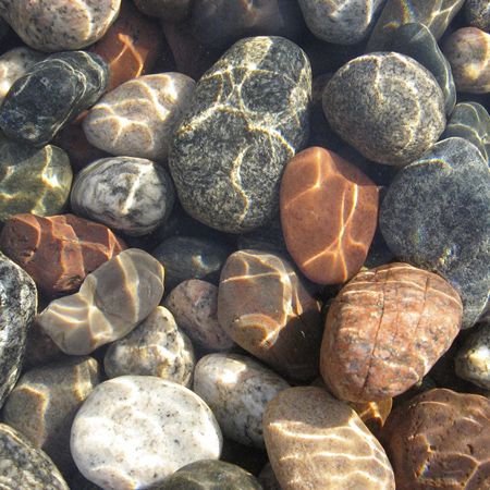 some rocks and pebbles are laying on top of each other in the water at the beach