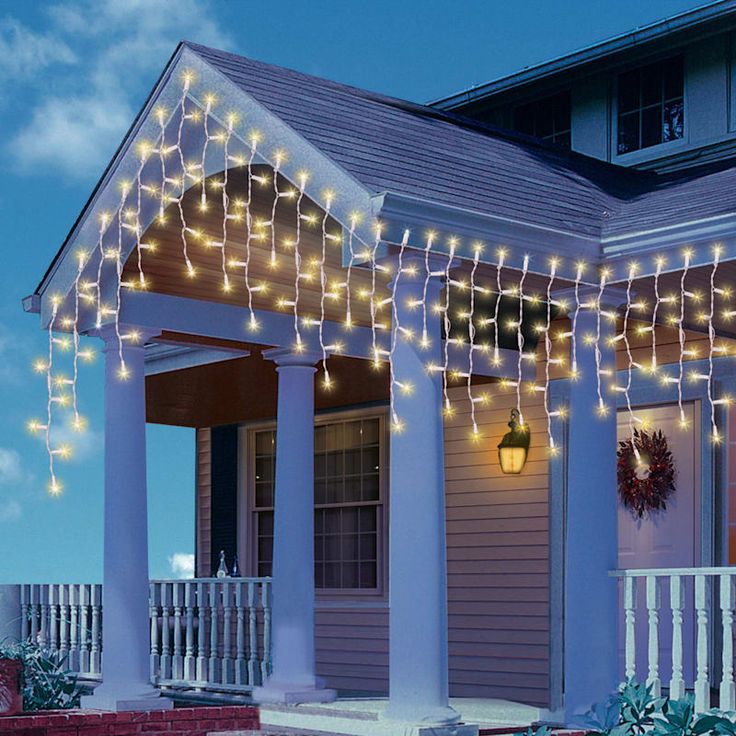 a house with christmas lights hanging from the front porch and on the side of it