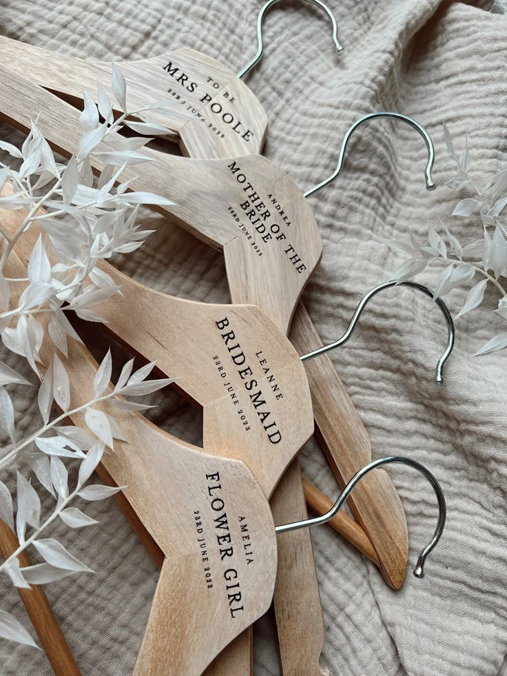 four wooden spoons with name tags on them sitting on a bed next to leaves