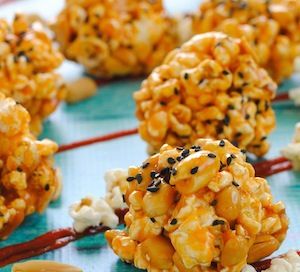 caramel popcorn balls with sprinkles and chocolate drizzled on them